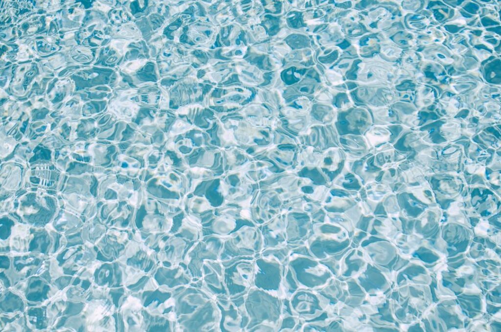 Crystal clear water surface with shimmering reflections, showcasing light play and texture, perfect for illustrating aquatic environments.