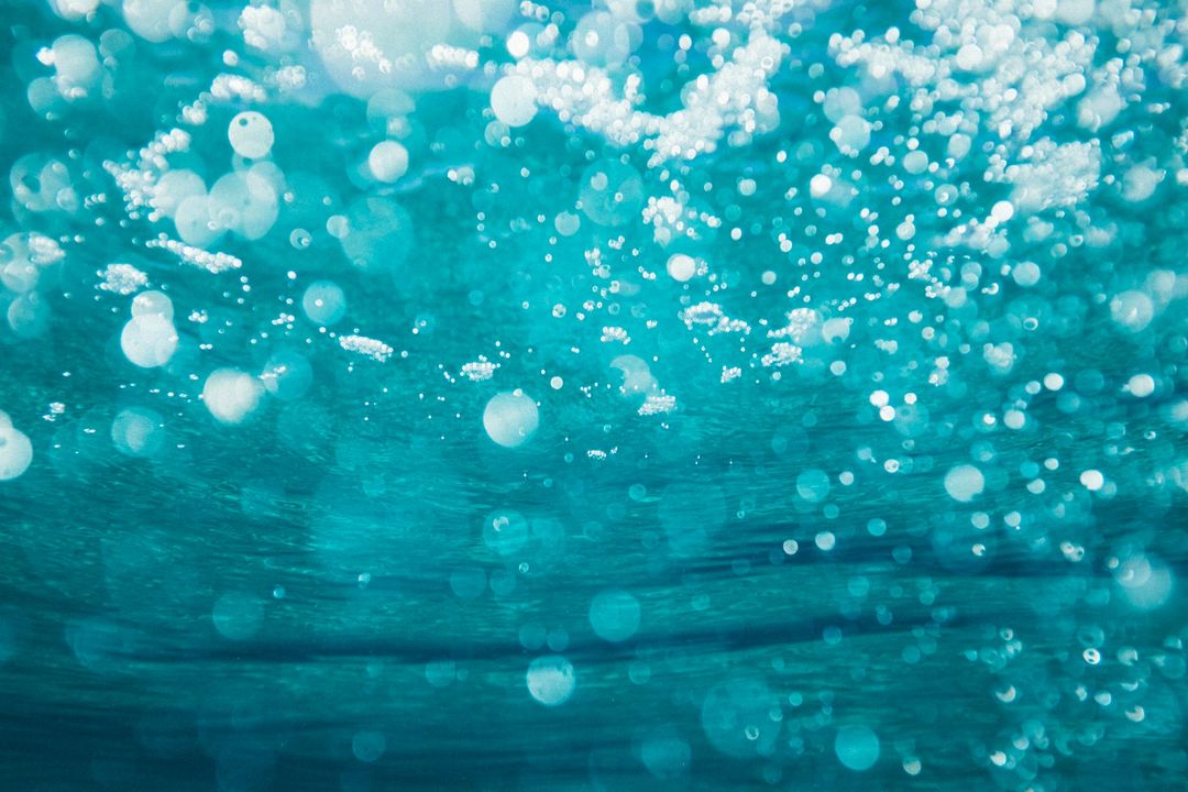 Bubbles float in a turquoise underwater scene, capturing light and creating a dreamy, tranquil atmosphere, ideal for a page about relaxation or nature.