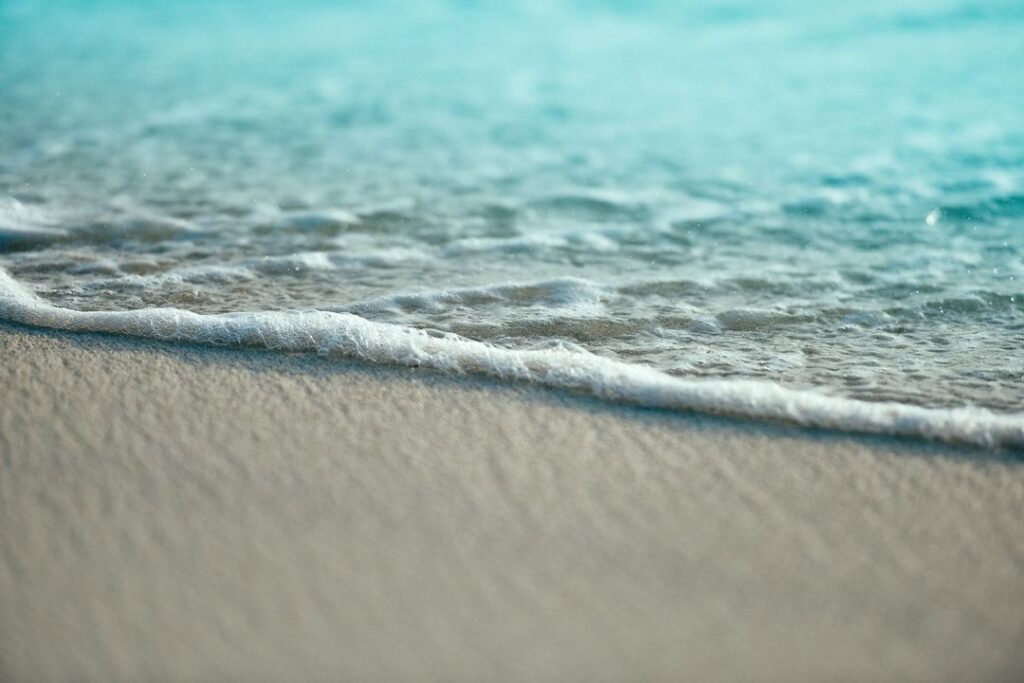 Gentle waves roll onto a sandy beach, creating a serene coastal scene that conveys relaxation and the beauty of nature.