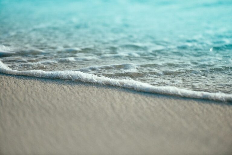 Gentle waves roll onto a sandy beach, creating a serene coastal scene that conveys relaxation and the beauty of nature.