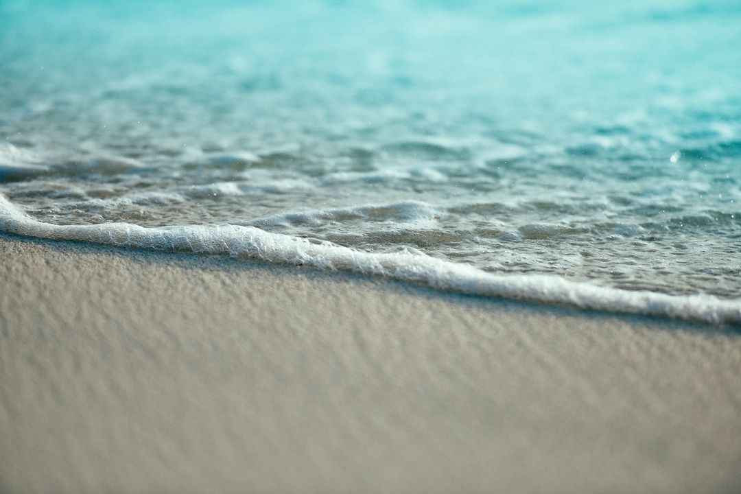 Gentle waves roll onto a sandy beach, creating a serene coastal scene that conveys relaxation and the beauty of nature.