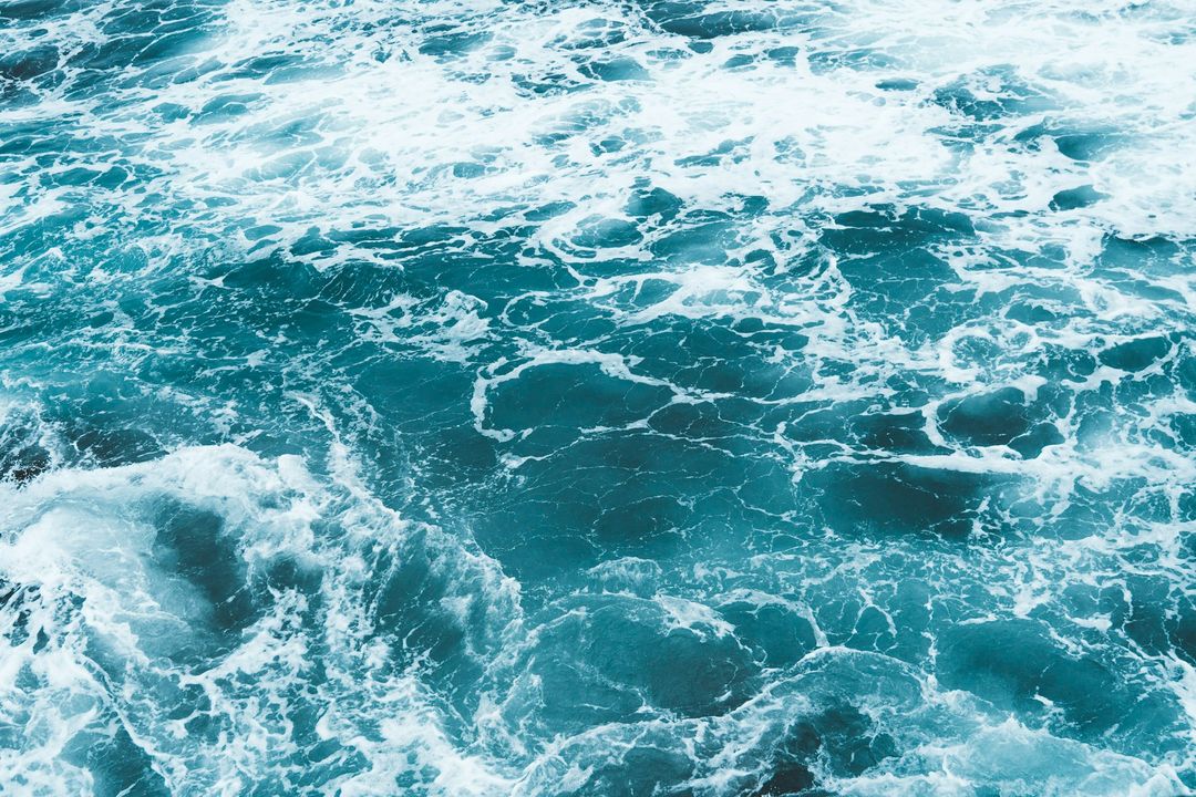 Turbulent ocean waves create dynamic patterns in vibrant turquoise water, showcasing the power and beauty of the sea.